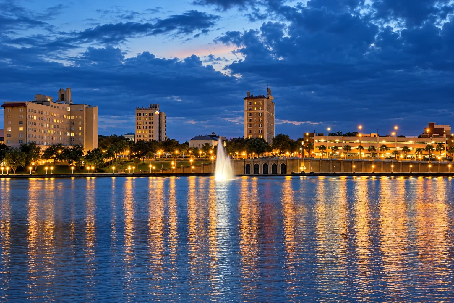 Downtown Lakeland and the Lake Mirror fountain at dusk, with lights reflecting across the water